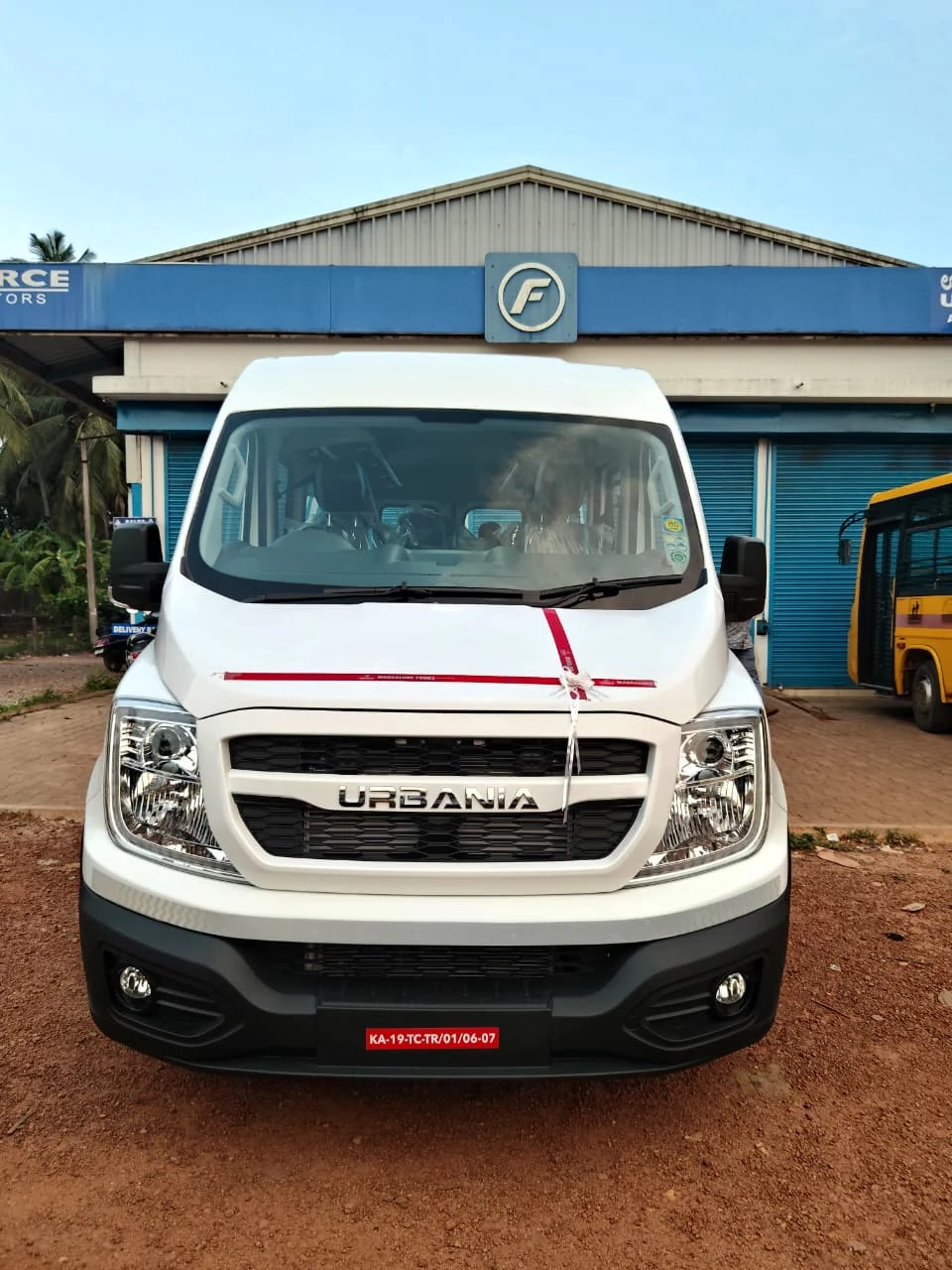 Brand new pristine white Force Urbania luxury tourist van at showroom delivery in Karnataka
