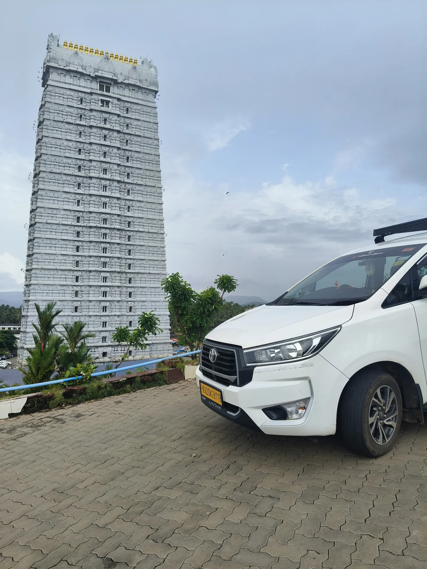 Atharv Cabs cab parked in front of towering white Murudeshwar Raja Gopura