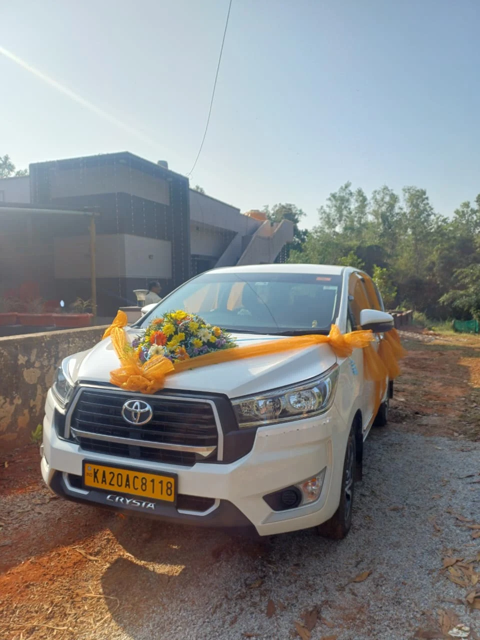Front 3/4 view of floral decorated wedding Innova Crysta parked at banquet hall entrance