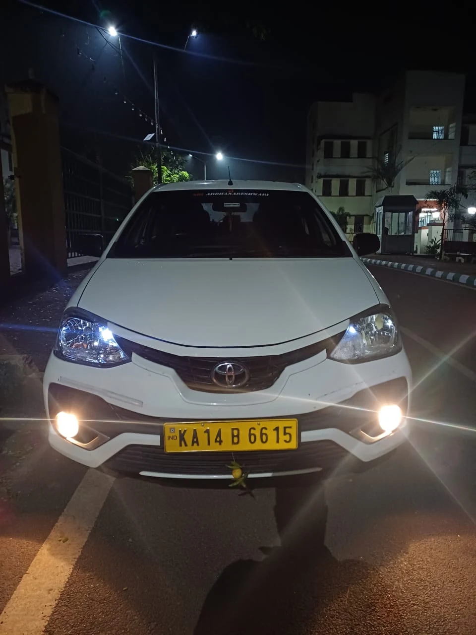 Toyota Etios sedan night view with headlights and fog lamps lit outside residence