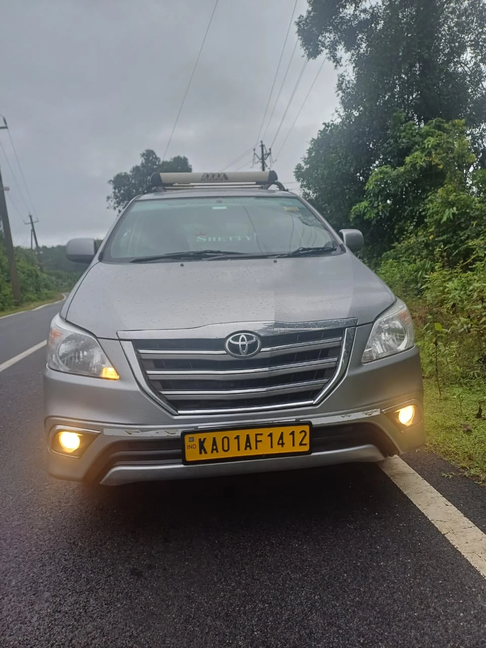Silver Toyota Innova cab on scenic mountain road in misty rainforest weather
